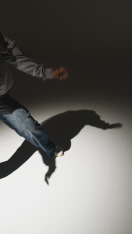 Vertical-Video-Studio-Portrait-Shot-Of-Young-Woman-Dancer-Dancing-With-Low-Key-Lighting-Against-Black-Background